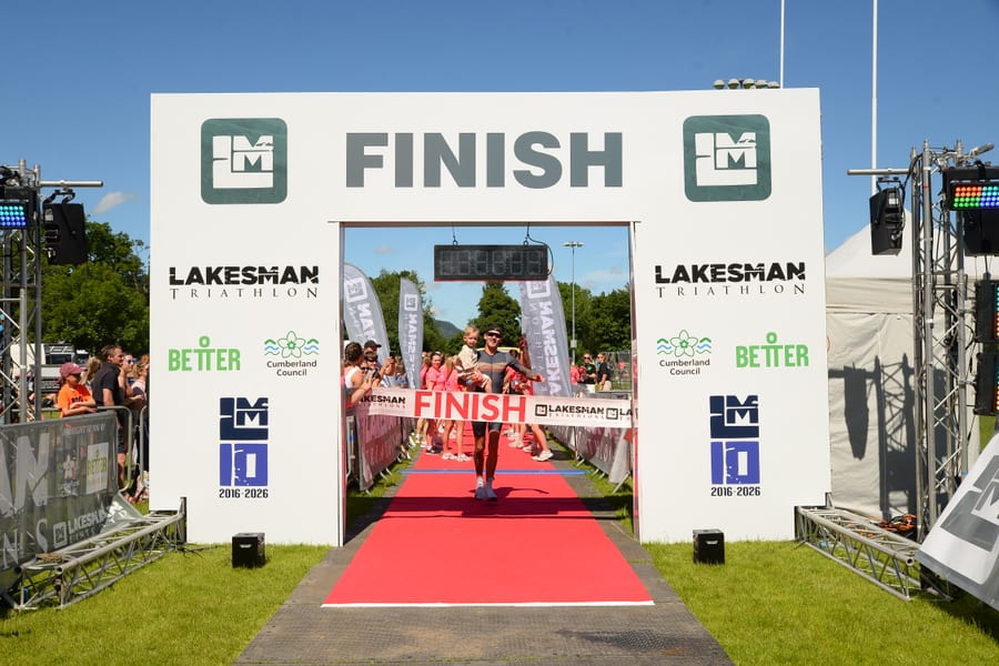 Athlete running down the red carpet to the Lakesman finish gantry