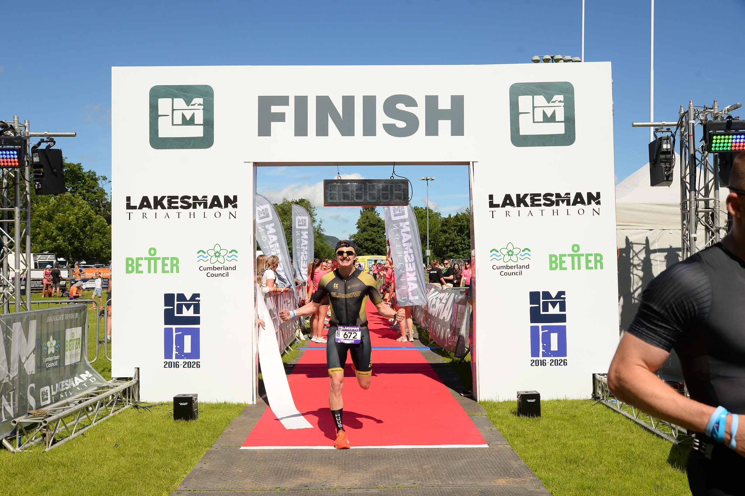 Athlete running down the red carpet through the Lakesman finish gantry