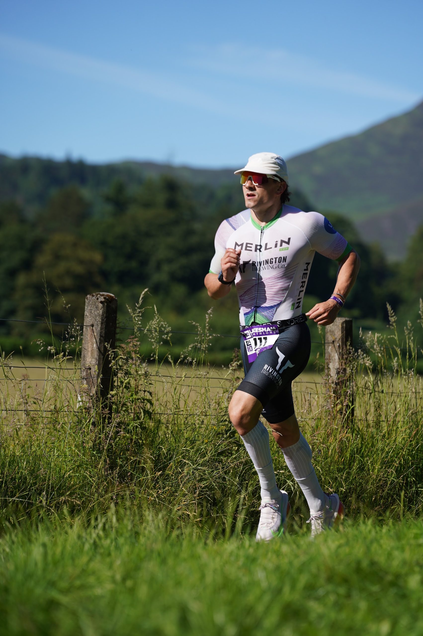 Runner in a Lakesman tri suit on the run course with the Lake District fells behind